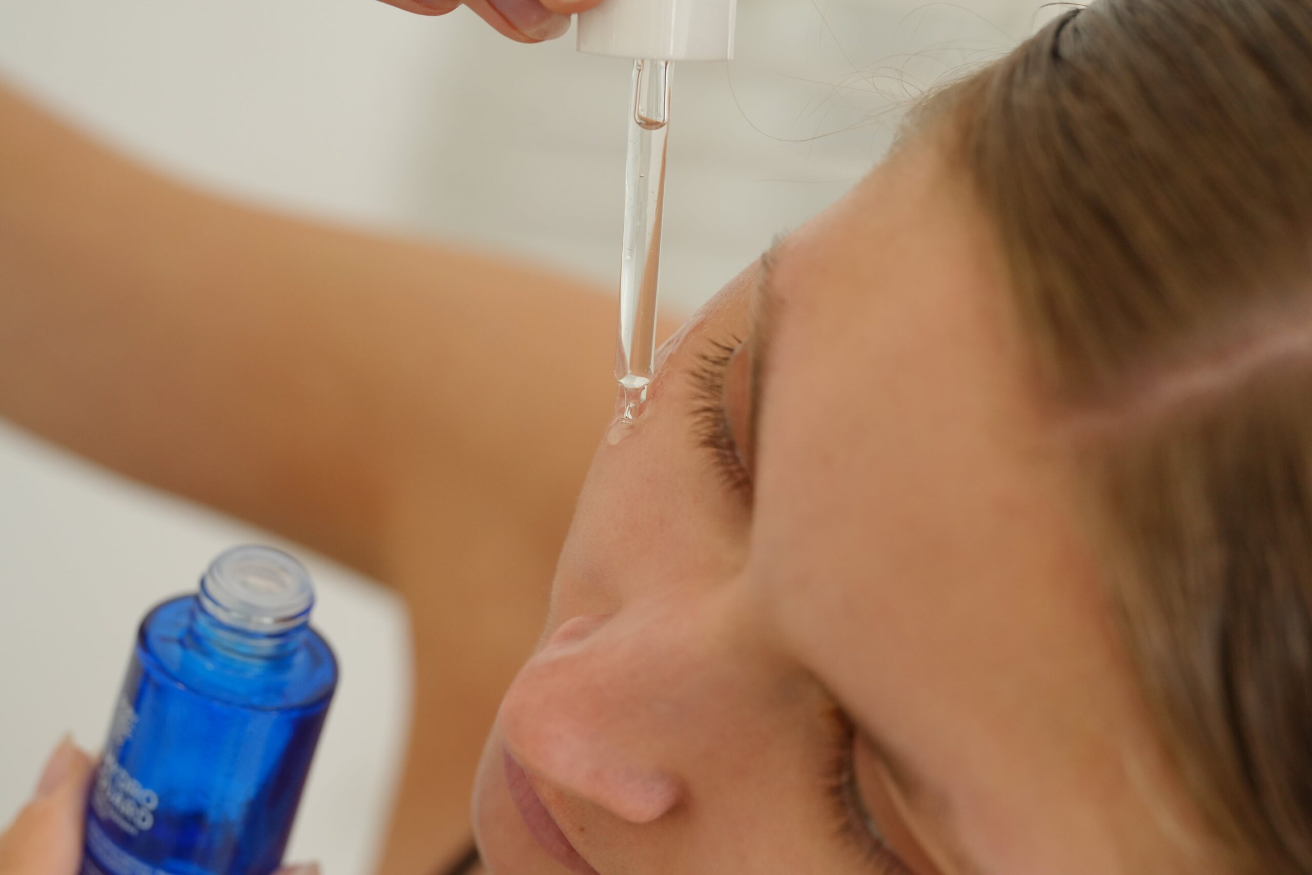 A close-up shot of a person applying a serum with a dropper, demonstrating how to layer products for the best results in a skincare routine for oily skin.