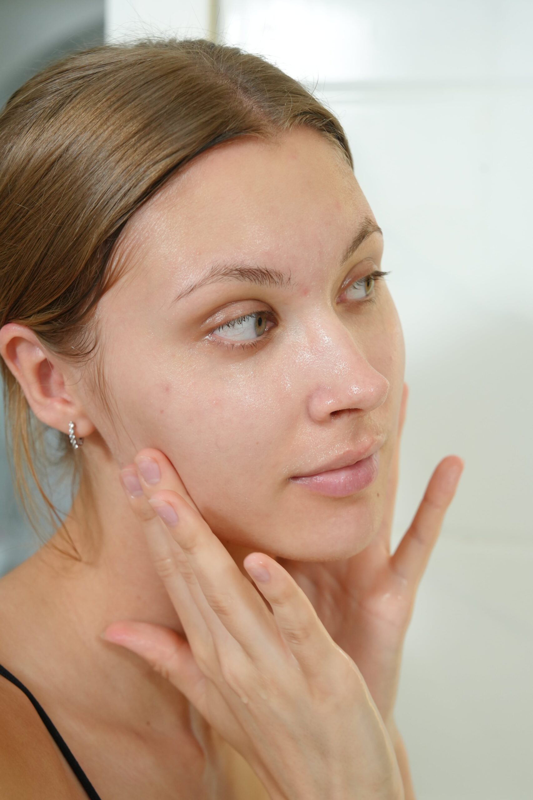 A person gently massages her face with her fingers, showing the soft, upward motion to follow when using moisturizer for oily skin.