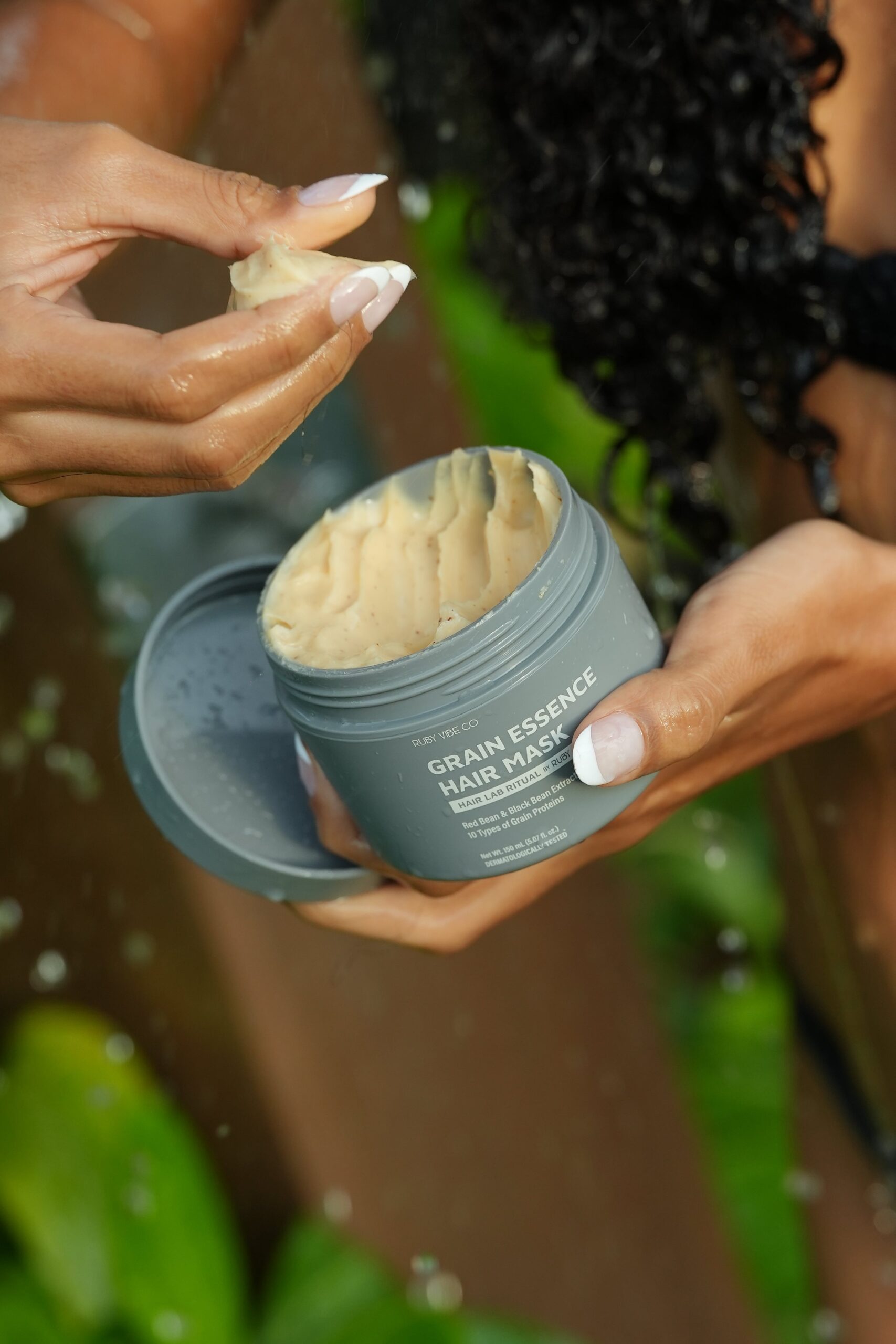 Hands preparing to apply Ruby Vibe Co. Grain Essence Hair Mask, showing the rich texture of the product as part of a comprehensive hair loss treatment.