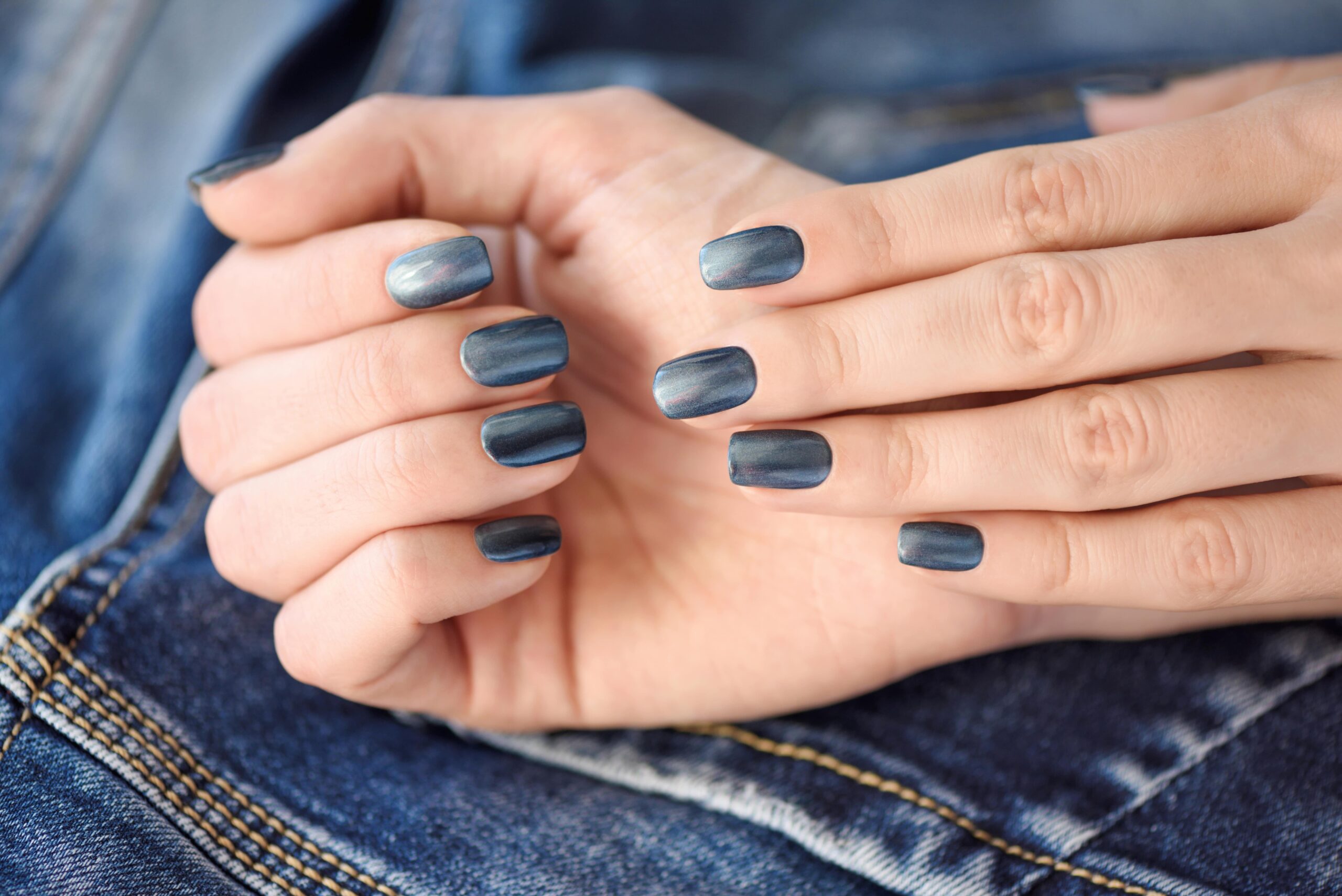 DIY chrome nails: A close-up of hands with a finished dark blue chrome manicure on short, square nails.