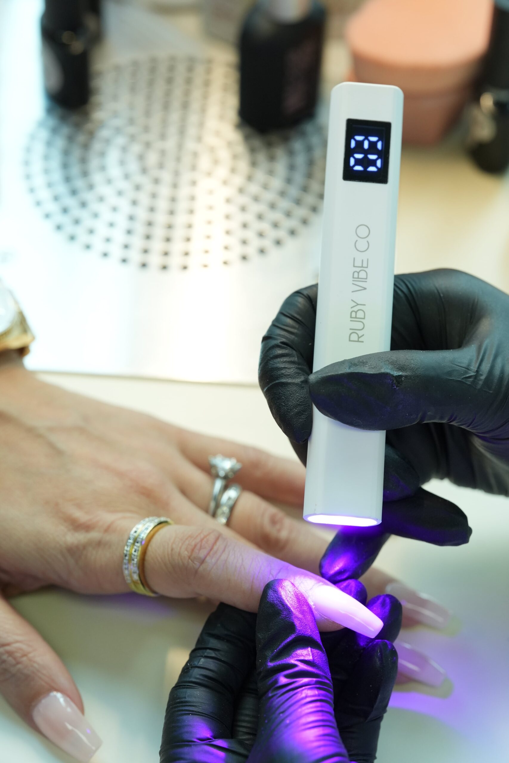 DIY chrome nails: Curing an extended nail under a portable UV lamp to set the gel layers.