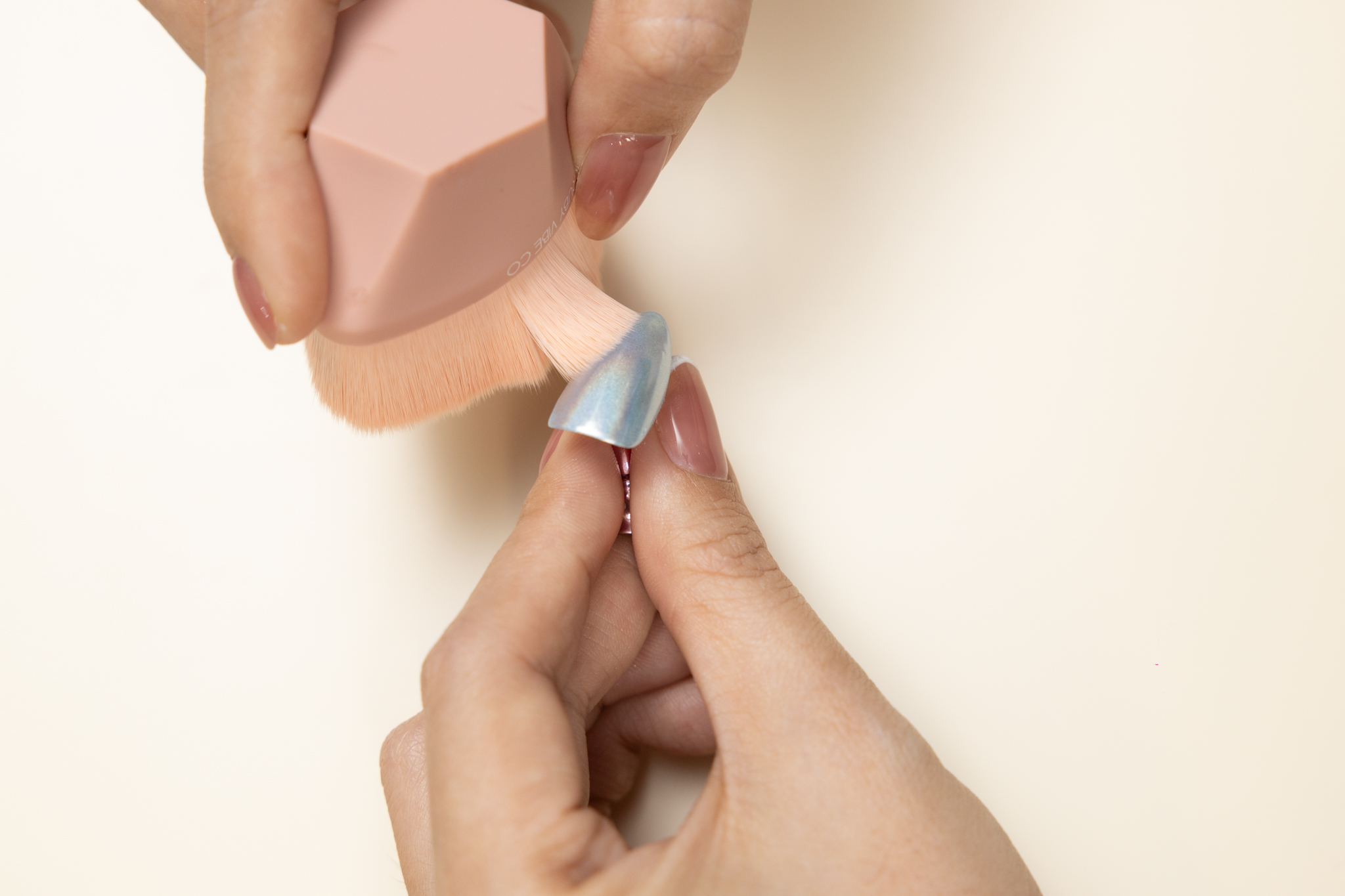 DIY chrome nails: Brushing off excess chrome powder from a nail using a soft brush for a clean look.