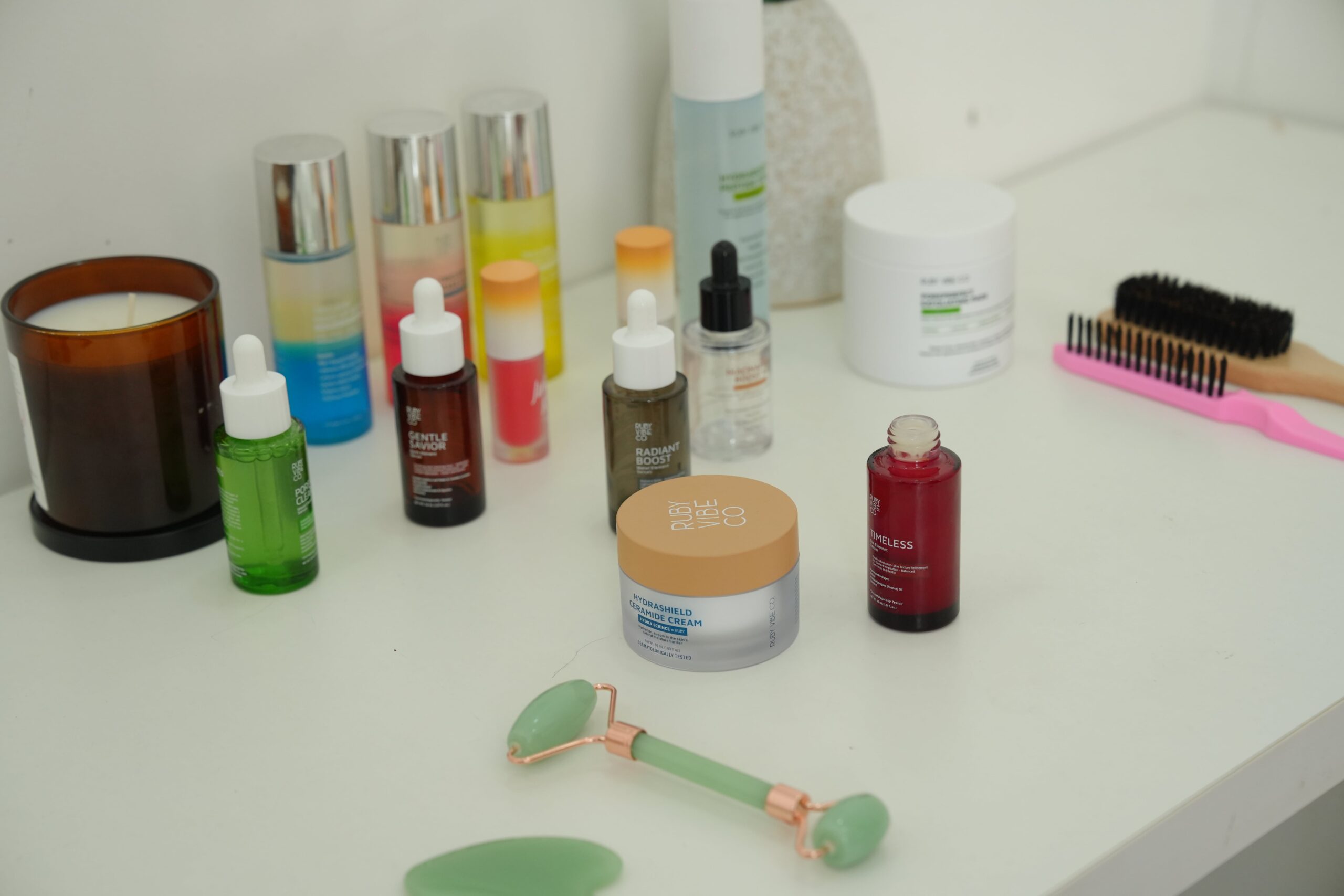 A collection of skincare products on a vanity, including a moisturizer, serums, and a jade roller, symbolizing a complete routine to manage oily skin.