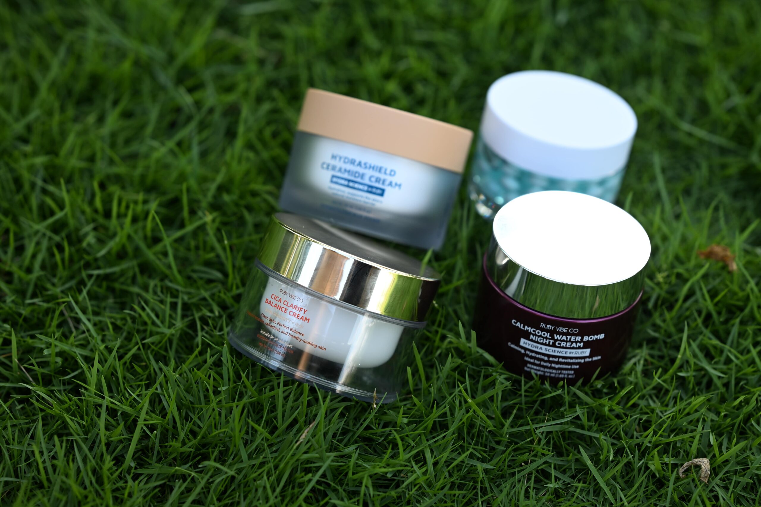 A selection of moisturizers for oily skin, including the Calmcool Water Bomb and Cica Clarify Balance Cream, displayed on grass for a product review.